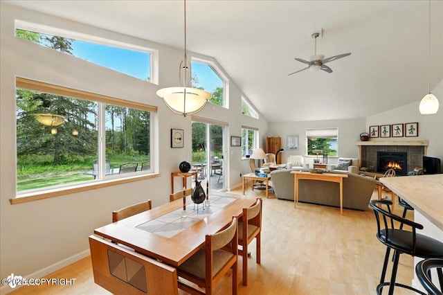 48585 Runners Ave, Soldotna, AK 99669 - dining space with light wood-style flooring, high vaulted ceiling, a ceiling fan, a fireplace, and baseboards