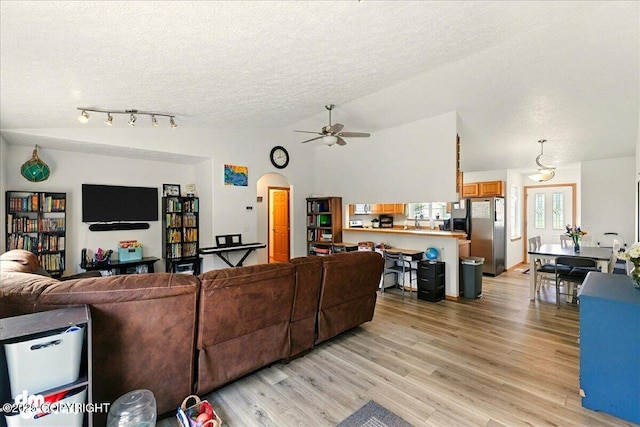 1213 Channel Way, Kenai, AK 99611 - living area with a textured ceiling, light wood-style floors, a ceiling fan, vaulted ceiling, and arched walkways