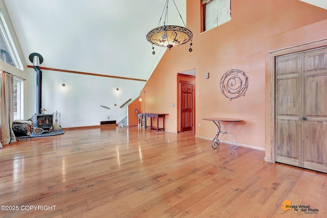 7408 N Grouse Loop, Wasilla, AK 99654 - unfurnished living room featuring a towering ceiling, a wood stove, hardwood / wood-style floors, and stairs