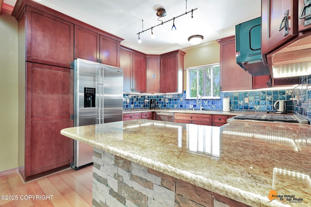 7408 N Grouse Loop, Wasilla, AK 99654 - kitchen with stainless steel appliances, backsplash, light stone counters, reddish brown cabinets, and light wood-style flooring