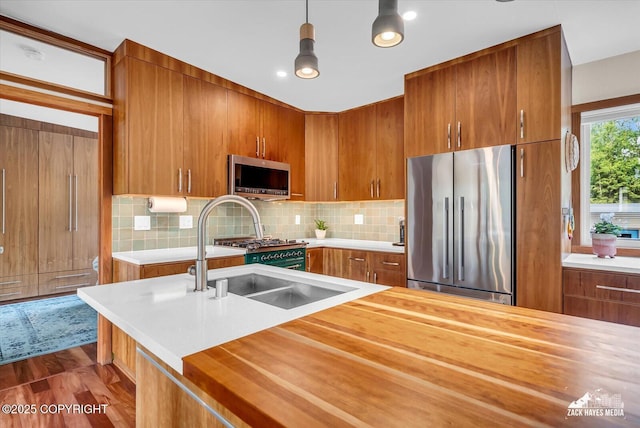 1601 Bannister Dr, Anchorage, AK 99508 - kitchen featuring stainless steel appliances, wooden counters, brown cabinetry, backsplash, and a sink