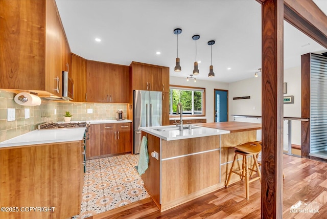1601 Bannister Dr, Anchorage, AK 99508 - kitchen featuring appliances with stainless steel finishes, a sink, light countertops, brown cabinets, and decorative backsplash