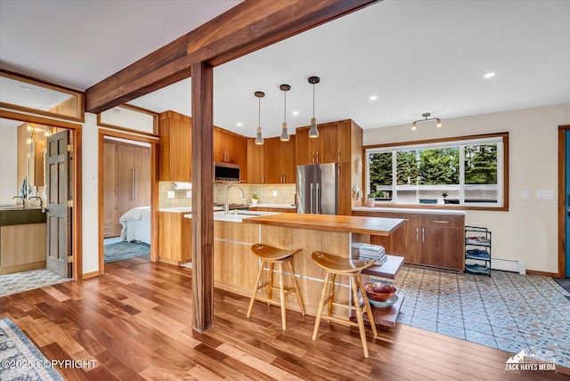1601 Bannister Dr, Anchorage, AK 99508 - kitchen featuring stainless steel appliances, light wood-type flooring, backsplash, brown cabinetry, and baseboards