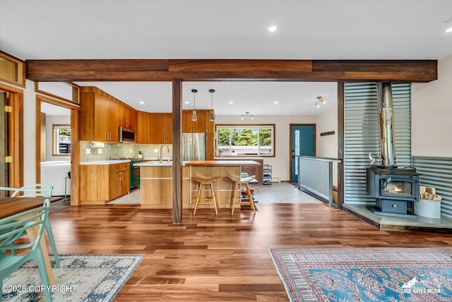 1601 Bannister Dr, Anchorage, AK 99508 - kitchen with stainless steel appliances, wood finished floors, light countertops, a wood stove, and brown cabinets