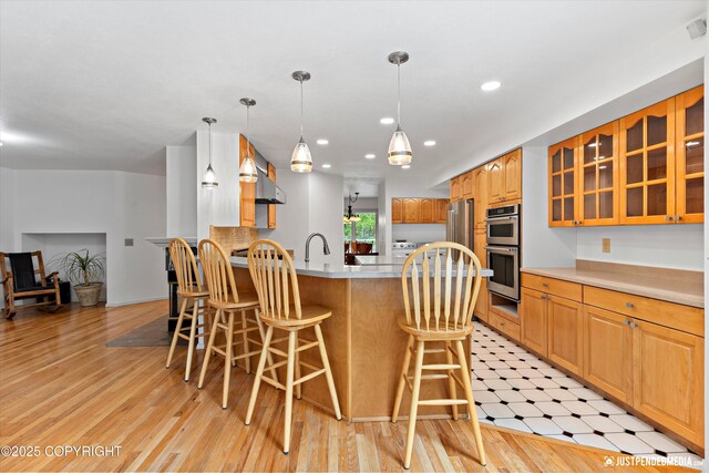 1701 Woo Blvd, Anchorage, AK 99515 - kitchen featuring glass insert cabinets, a breakfast bar area, a peninsula, appliances with stainless steel finishes, and light countertops