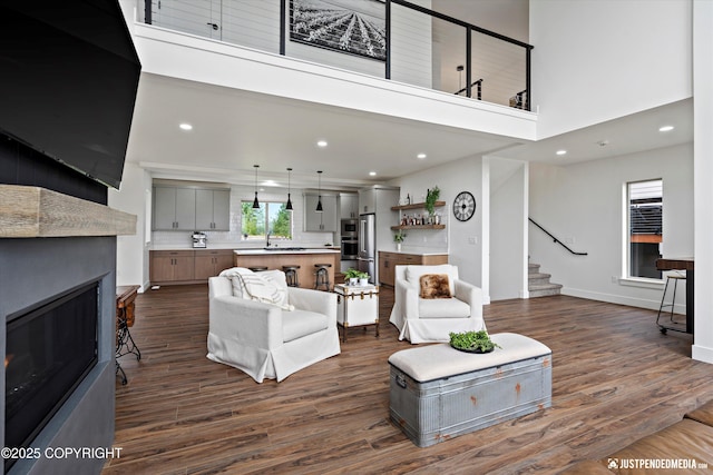 7864 Crane Cir, Anchorage, AK 99502 - living room featuring stairs, dark wood-style flooring, a fireplace, recessed lighting, and a towering ceiling