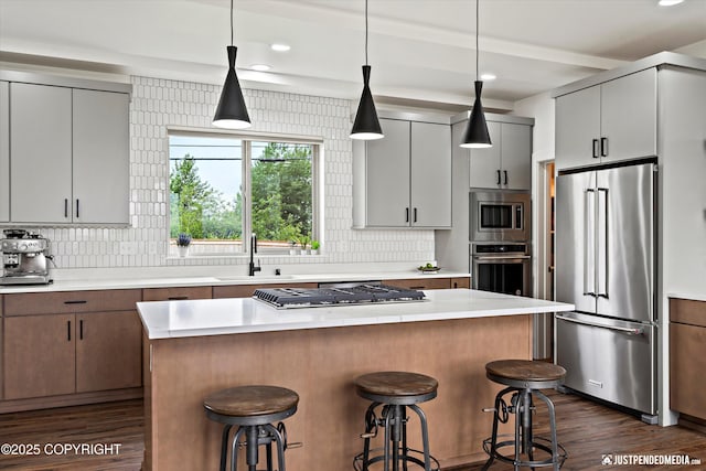 7864 Crane Cir, Anchorage, AK 99502 - kitchen featuring appliances with stainless steel finishes, dark wood-style flooring, decorative backsplash, light countertops, and a kitchen breakfast bar