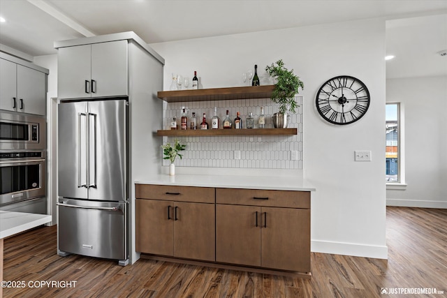 7864 Crane Cir, Anchorage, AK 99502 - kitchen featuring appliances with stainless steel finishes, dark wood-style floors, light countertops, open shelves, and tasteful backsplash
