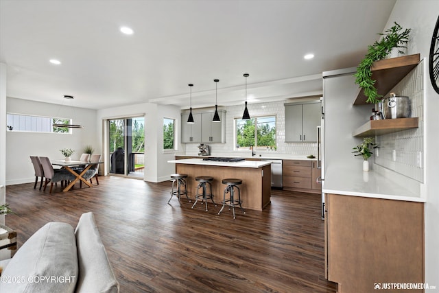 7864 Crane Cir, Anchorage, AK 99502 - kitchen with dishwasher, a kitchen island, tasteful backsplash, dark wood-style flooring, and light countertops