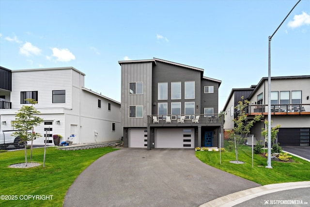 7864 Crane Cir, Anchorage, AK 99502 - view of front of home with board and batten siding, driveway, an attached garage, and a front lawn