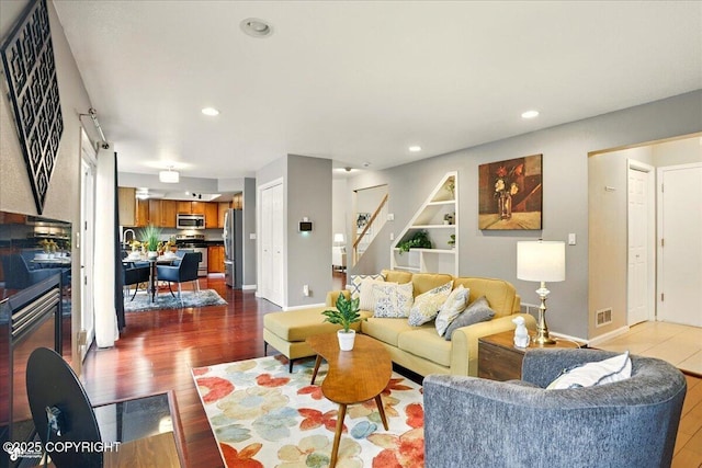 2350 Ariel Cir, Anchorage, AK 99515 - living room featuring wood finished floors, stairway, recessed lighting, baseboards, and built in features