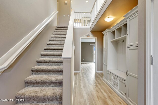 5893 Kenai Fjords Loop, Anchorage, AK 99502 - staircase featuring a towering ceiling, wood finished floors, and baseboards
