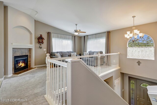 5893 Kenai Fjords Loop, Anchorage, AK 99502 - carpeted living area with vaulted ceiling, a ceiling fan, a tiled fireplace, a chandelier, and baseboards