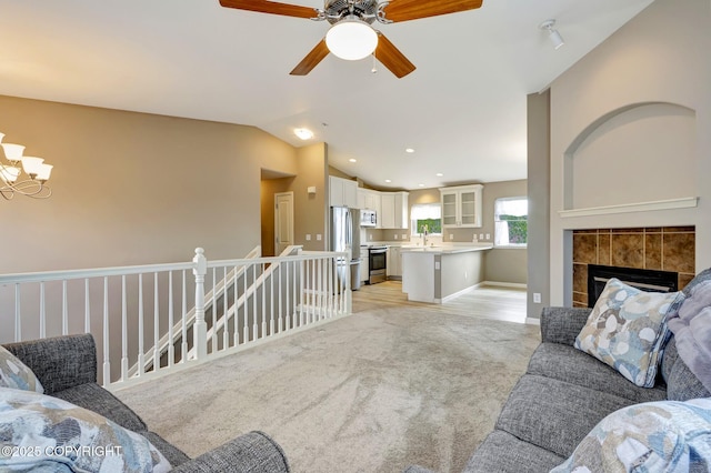 5893 Kenai Fjords Loop, Anchorage, AK 99502 - living area with light colored carpet, a ceiling fan, a tiled fireplace, lofted ceiling, and a chandelier