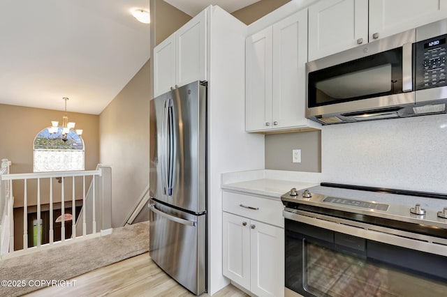 5893 Kenai Fjords Loop, Anchorage, AK 99502 - kitchen featuring stainless steel appliances, light wood finished floors, a chandelier, and white cabinetry