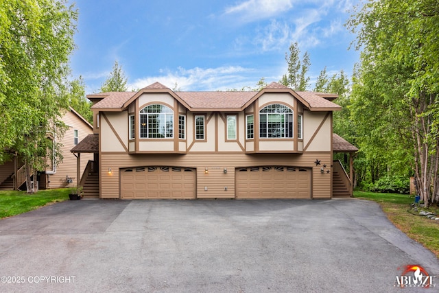 4106 E Country Fair Dr # A, Wasilla, AK 99654 - tudor-style house featuring stairs, an attached garage, stucco siding, and a shingled roof