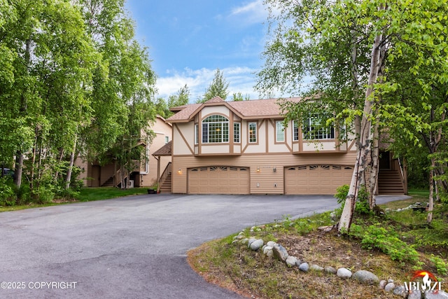 4106 E Country Fair Dr # A, Wasilla, AK 99654 - tudor home with stairway, an attached garage, asphalt driveway, and a shingled roof