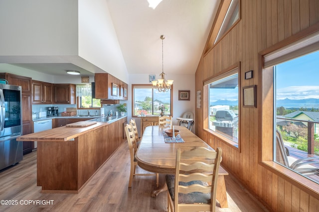 292 Mountain View Dr, Homer, AK 99603 - dining space with high vaulted ceiling, light wood finished floors, a chandelier, and wooden walls
