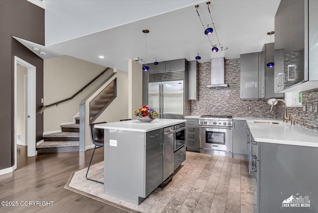268 Dailey Ave, Anchorage, AK 99515 - kitchen featuring gray cabinets, high end appliances, wall chimney exhaust hood, a center island, and light wood-style flooring