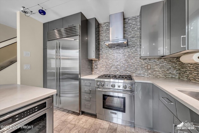 268 Dailey Ave, Anchorage, AK 99515 - kitchen with stainless steel appliances, gray cabinets, wall chimney range hood, and backsplash