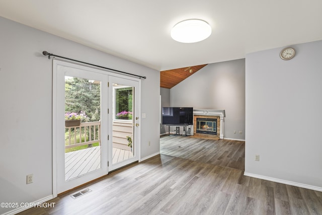 11751 Mary Ave, Anchorage, AK 99515 - unfurnished living room featuring wood finished floors, a tile fireplace, and vaulted ceiling
