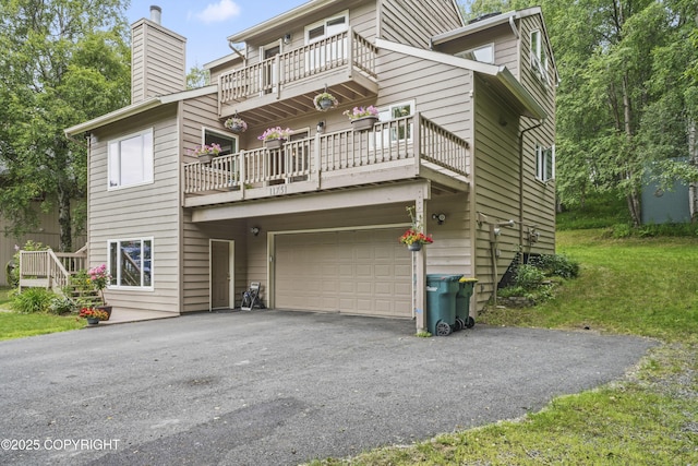11751 Mary Ave, Anchorage, AK 99515 - rear view of house with a balcony, a chimney, asphalt driveway, and an attached garage