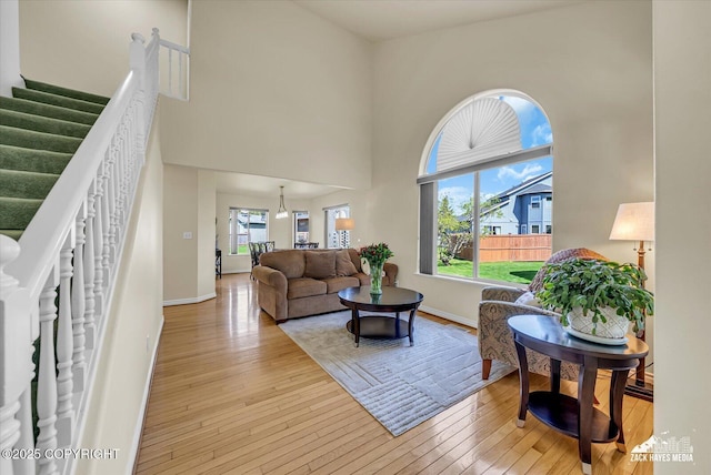10201 Sextant Cir, Anchorage, AK 99515 - living room with stairs, plenty of natural light, hardwood / wood-style flooring, a towering ceiling, and baseboards