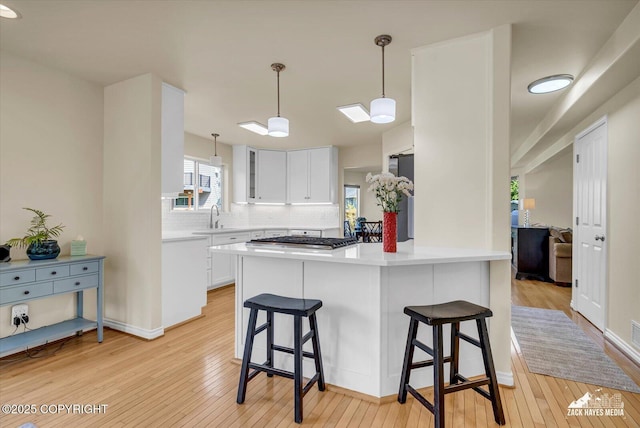 10201 Sextant Cir, Anchorage, AK 99515 - kitchen featuring a kitchen bar, light wood finished floors, white cabinets, and tasteful backsplash
