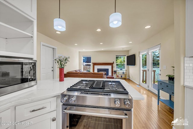 10201 Sextant Cir, Anchorage, AK 99515 - kitchen featuring stainless steel appliances, a fireplace, white cabinets, light wood finished floors, and open floor plan
