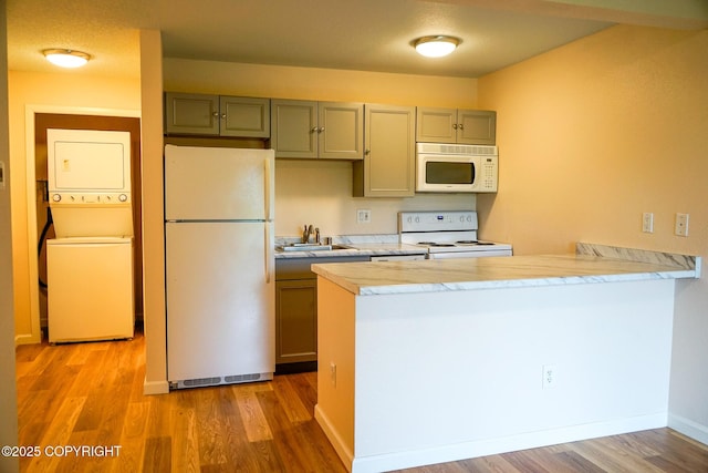 2100 Minerva Way # A6, Anchorage, AK 99515 - kitchen featuring white appliances, estacked washer and dryer, light wood-type flooring, a sink, and a peninsula