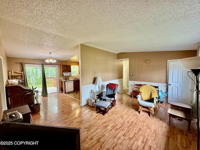 4941 E Rhubarb Cir, Wasilla, AK 99654 - living room with light wood-style flooring, a textured ceiling, a chandelier, and wainscoting