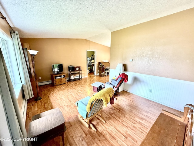 4941 E Rhubarb Cir, Wasilla, AK 99654 - living area with a baseboard radiator, wood finished floors, a wainscoted wall, lofted ceiling, and a textured ceiling