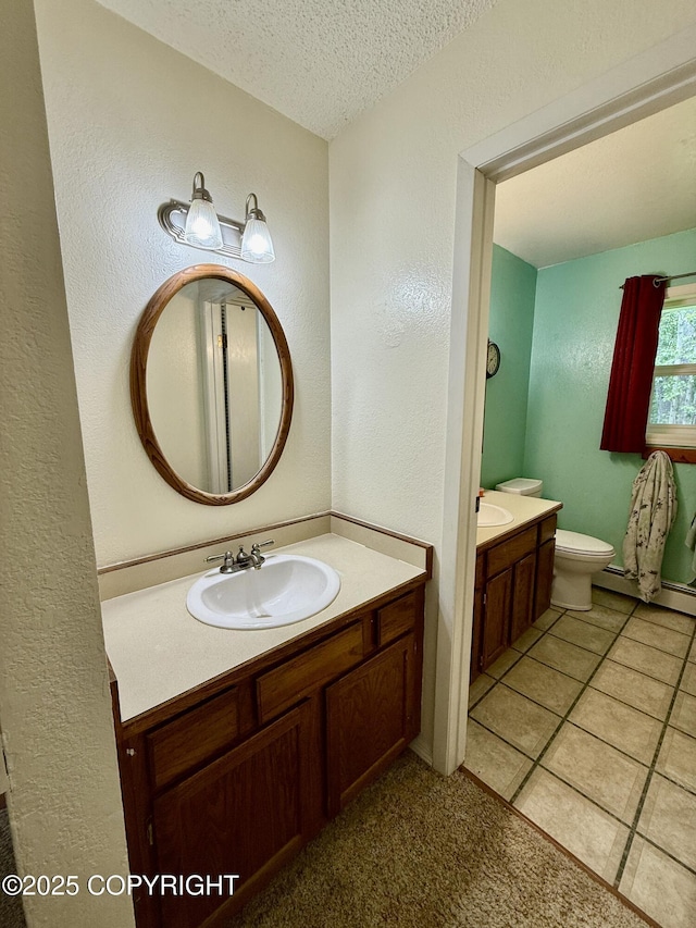 4941 E Rhubarb Cir, Wasilla, AK 99654 - bathroom with vanity, a baseboard heating unit, a textured ceiling, a textured wall, and tile patterned flooring