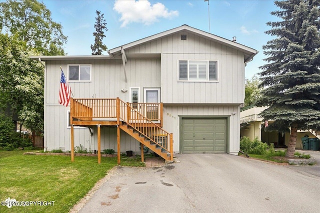 6911 Cheryl St, Anchorage, AK 99518 - view of front of property with driveway, an attached garage, stairs, a front yard, and a wooden deck
