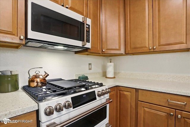 6911 Cheryl St, Anchorage, AK 99518 - kitchen with white microwave, stainless steel gas stove, and brown cabinetry