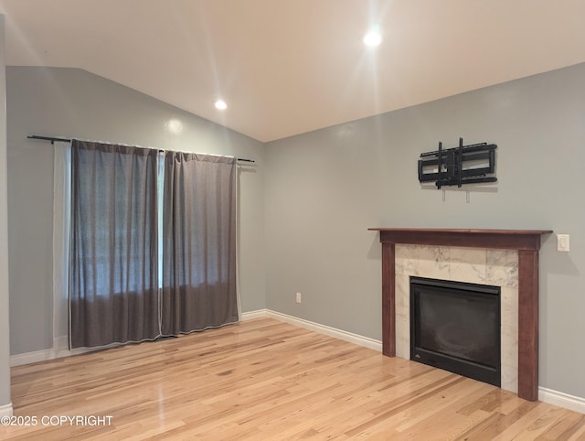 7324 Zurich St, Anchorage, AK 99507 - unfurnished living room featuring vaulted ceiling, wood finished floors, a tiled fireplace, recessed lighting, and baseboards