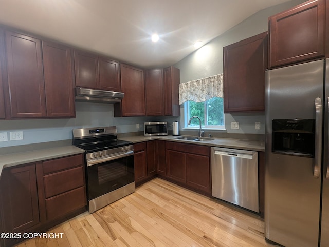 7324 Zurich St, Anchorage, AK 99507 - kitchen featuring stainless steel appliances, under cabinet range hood, a sink, light wood-style floors, and lofted ceiling