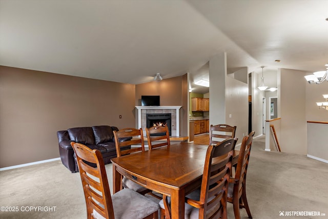 2353 Maritime Loop, Anchorage, AK 99515 - dining space featuring a chandelier, light carpet, a tiled fireplace, vaulted ceiling, and baseboards