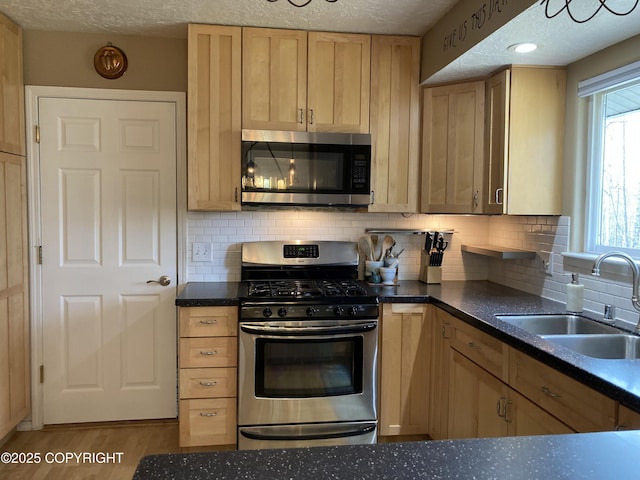 22909 Green Garden Dr, Chugiak, AK 99567 - kitchen with appliances with stainless steel finishes, a sink, dark countertops, backsplash, and light brown cabinetry