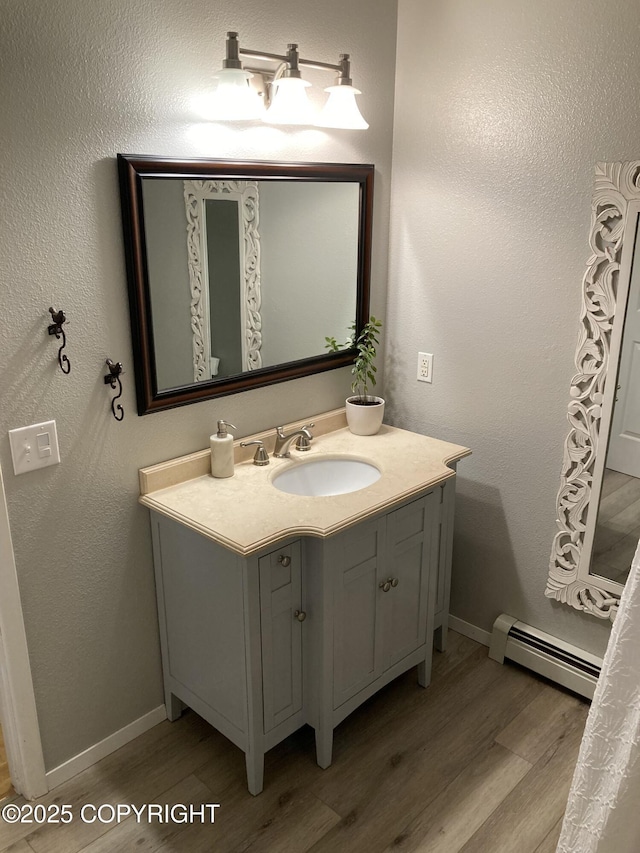 22909 Green Garden Dr, Chugiak, AK 99567 - bathroom featuring a baseboard heating unit, wood finished floors, vanity, and baseboards