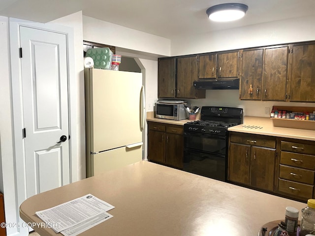 7700 E 32nd Ave, Anchorage, AK 99504 - kitchen with freestanding refrigerator, black gas range, stainless steel microwave, under cabinet range hood, and dark brown cabinetry