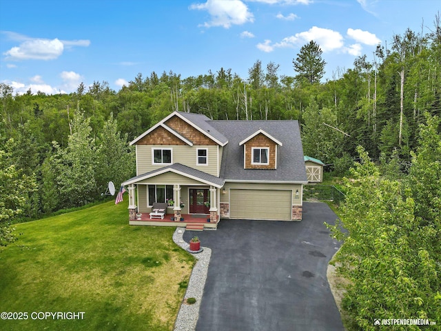 542 S Tender Arctic Dr, Palmer, AK 99645 - craftsman-style home featuring covered porch, a front lawn, a view of trees, asphalt driveway, and stone siding