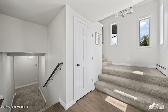 2105 W 47th Ave, Anchorage, AK 99517 - staircase featuring a baseboard heating unit, a chandelier, wood finished floors, and carpet floors