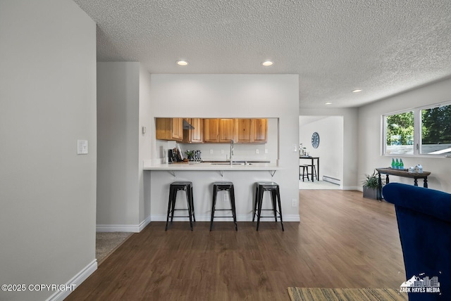 2105 W 47th Ave, Anchorage, AK 99517 - kitchen with a kitchen bar, dark wood finished floors, brown cabinetry, a textured ceiling, and recessed lighting