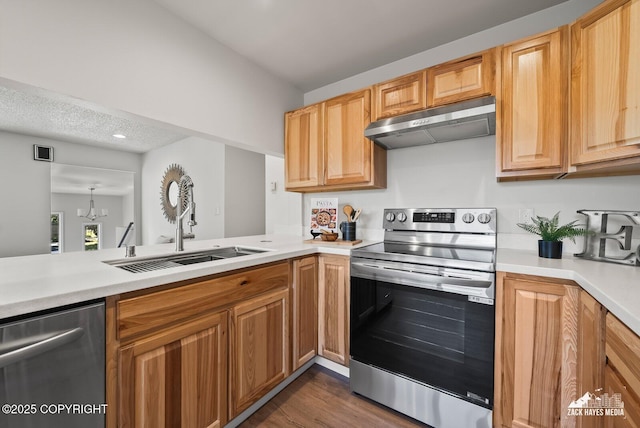 2105 W 47th Ave, Anchorage, AK 99517 - kitchen with under cabinet range hood, stainless steel appliances, light countertops, dark wood finished floors, and a chandelier