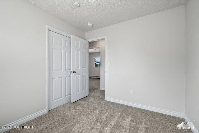 2105 W 47th Ave, Anchorage, AK 99517 - unfurnished bedroom featuring carpet, a closet, a textured ceiling, and a baseboard heating unit