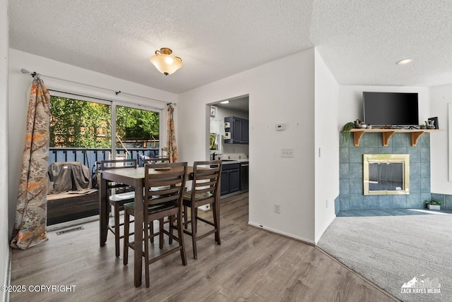 20213 David Ave, Eagle River, AK 99577 - dining space with wood finished floors, a textured ceiling, and a tiled fireplace