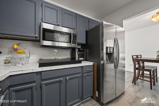 20213 David Ave, Eagle River, AK 99577 - kitchen with appliances with stainless steel finishes, light wood-type flooring, and tile counters