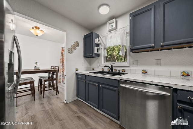 20213 David Ave, Eagle River, AK 99577 - kitchen with stainless steel appliances, tile counters, wood finished floors, and blue cabinetry