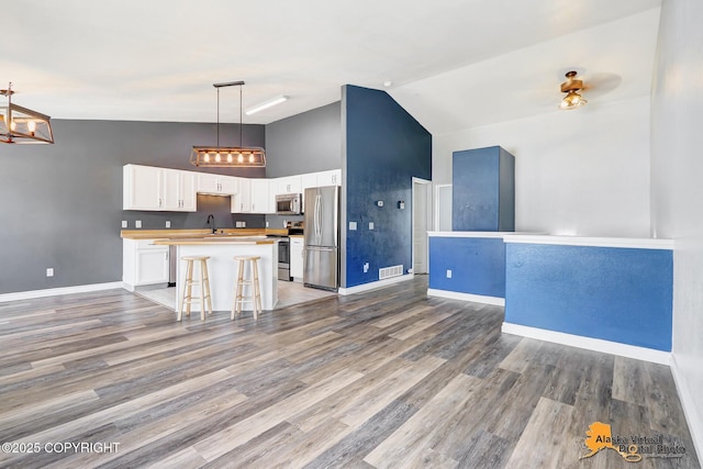 2922 Summer Sun Ct # 154, Anchorage, AK 99507 - kitchen with stainless steel appliances, high vaulted ceiling, white cabinets, a center island, and a chandelier